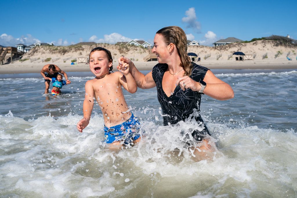 Mother and son play in the ocean at a Corolla beach